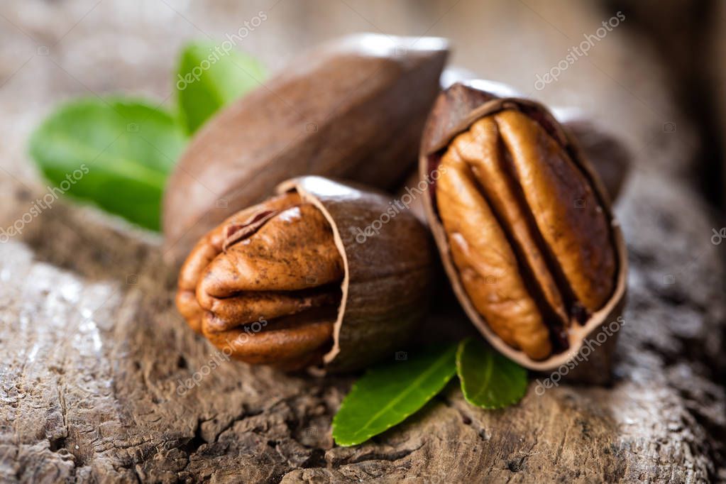 Pecanas enteras y troceadas sobre una tabla de madera.
